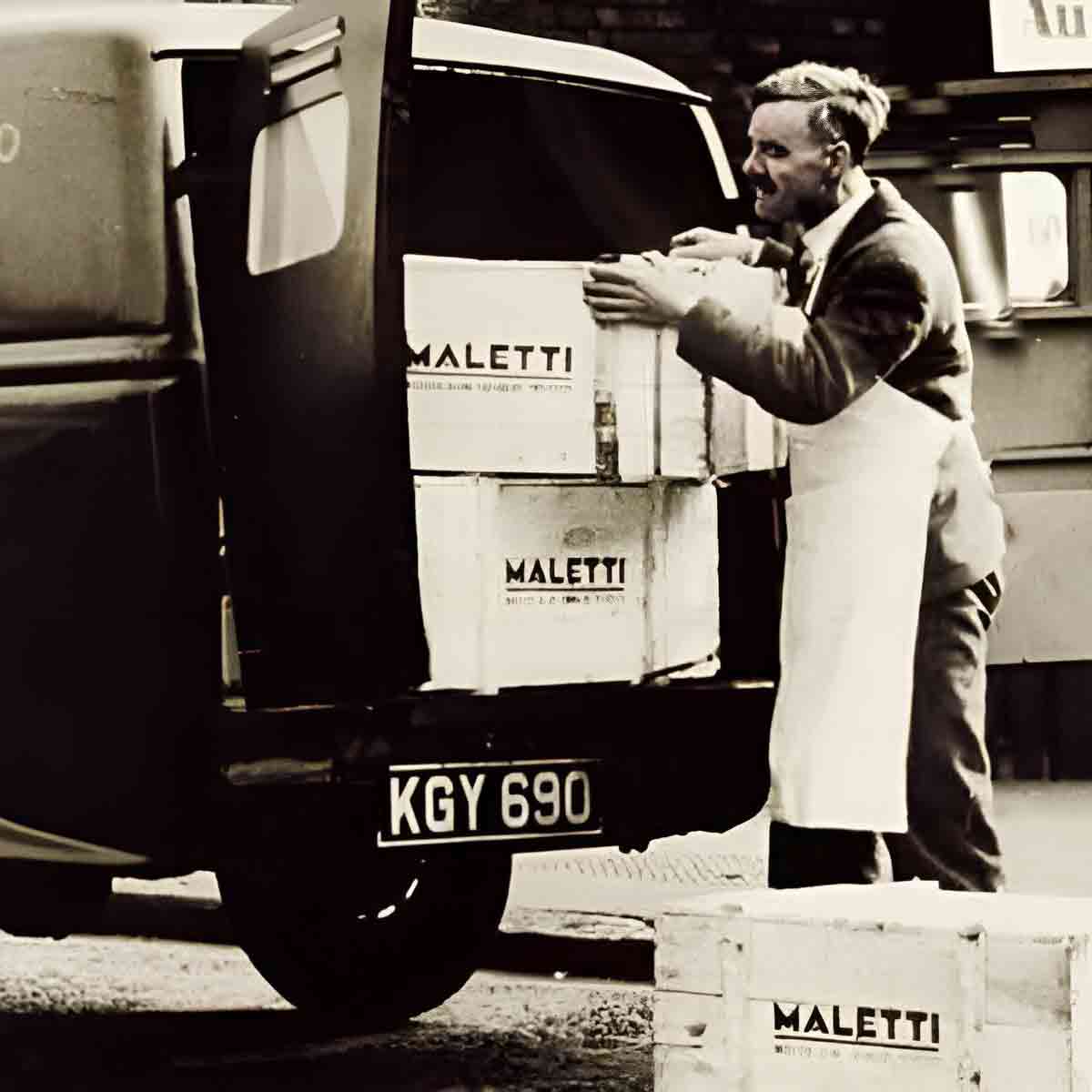 Mann lädt Maletti-Kisten in Lieferwagen.