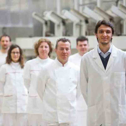 Mitarbeiter der Manufaktur in der Produktionshalle mit weißen hygienischen Kitteln.