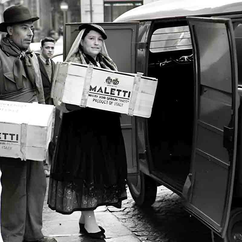 Personen laden Maletti-Kisten in Fahrzeug auf der Straße.