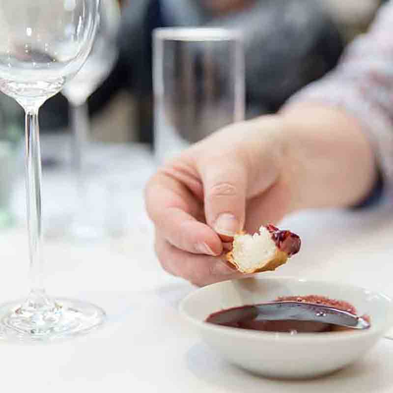 Hand hält Brot über Schale mit rotem Dip.