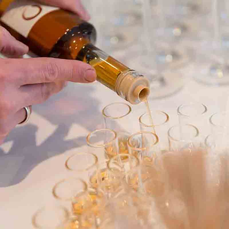 Person füllt Gläser mit Olivenöl aus Flasche.