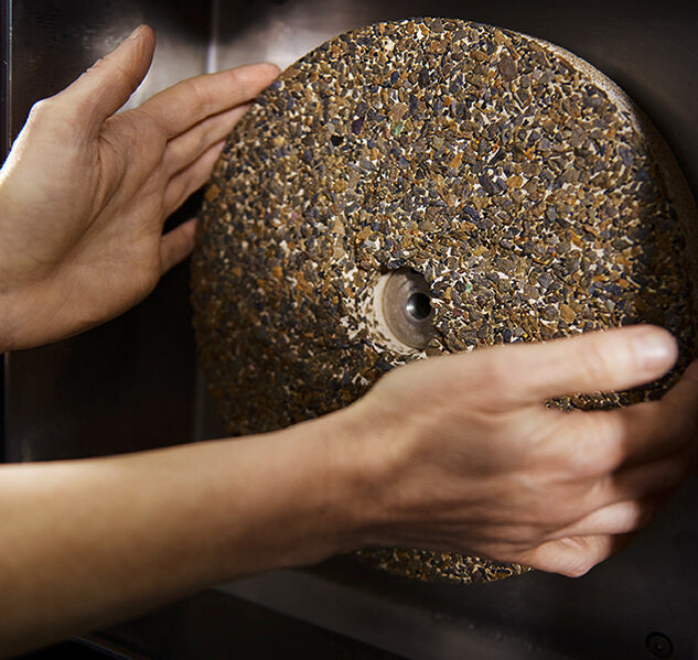 Hände halten Mühlstein in Nahaufnahme.