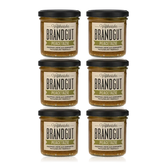 Sechs Gläser Brandgut Peacetazie Pistaziencreme auf weißem Hintergrund.