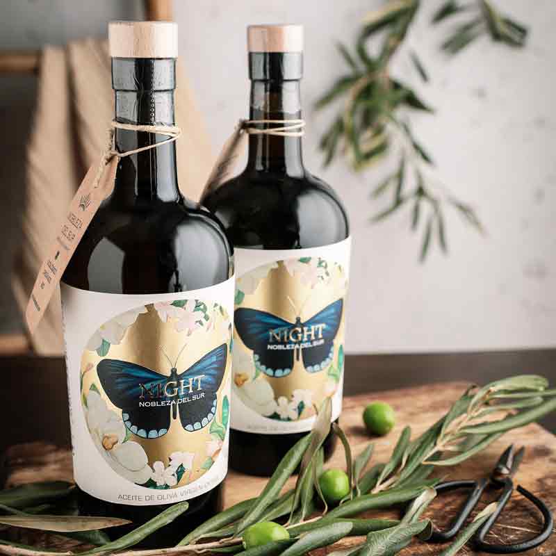 Zwei Flaschen Olivenöl mit Olivenzweigen dekoriert.