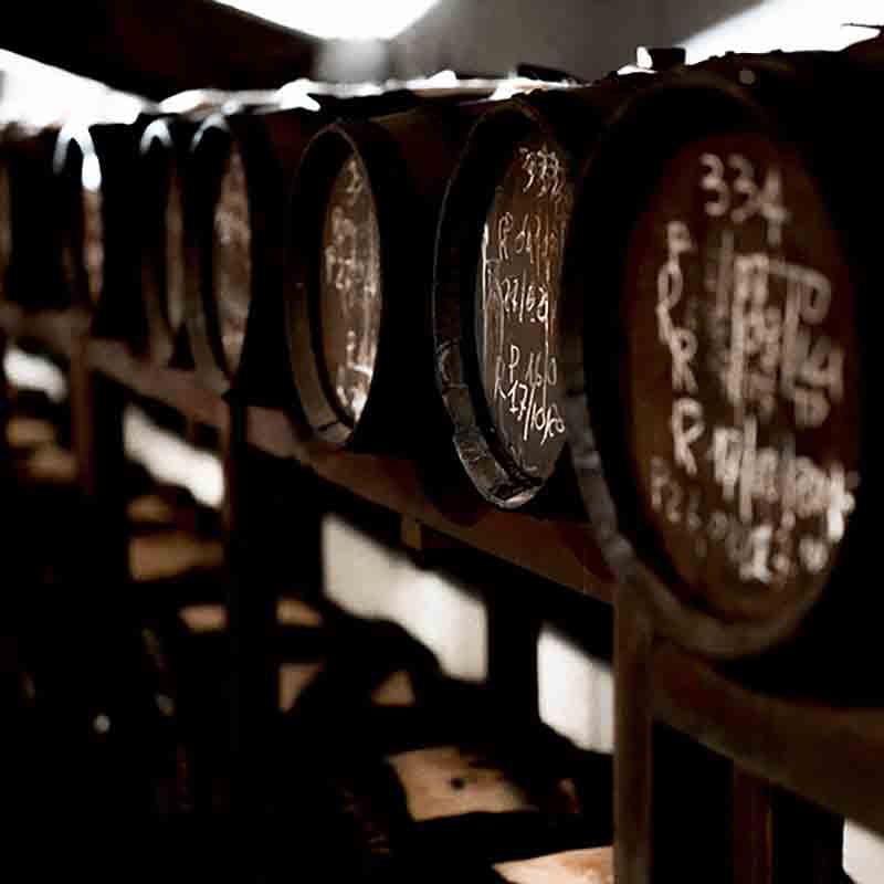 Holzfässer mit handgeschriebenen Notizen in dunklem Lagerraum.