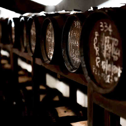 Holzfässer mit handgeschriebenen Notizen in dunklem Lagerraum.