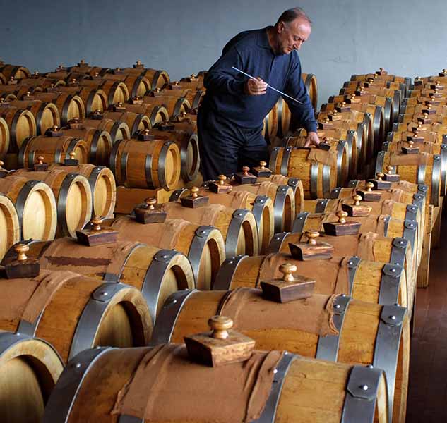 Mann prüft Essigfässer in Lagerhalle, Acetaia Delizia Estense.