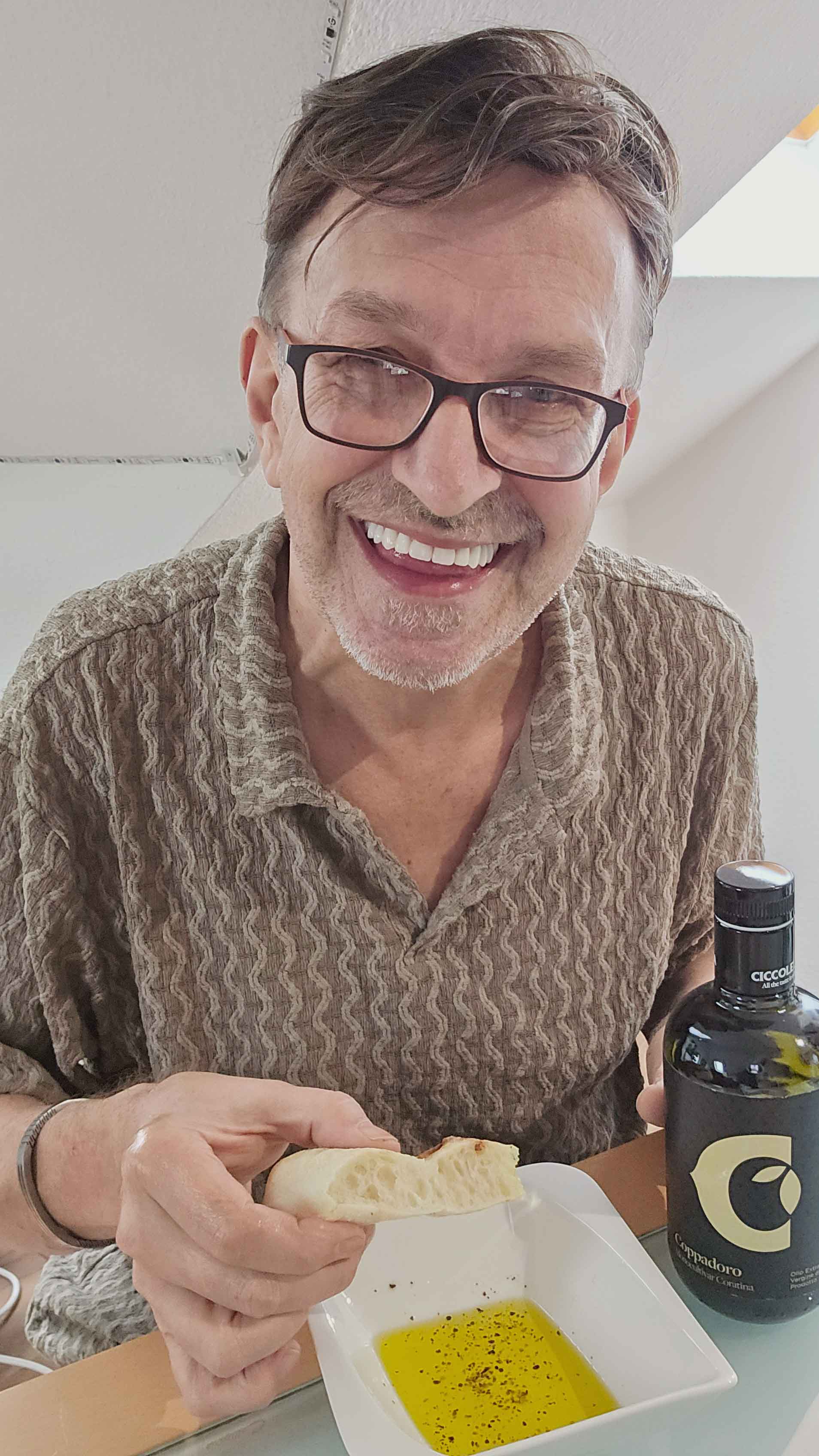 Ein lächelnder Mann probiert Olivenöl mit Brot