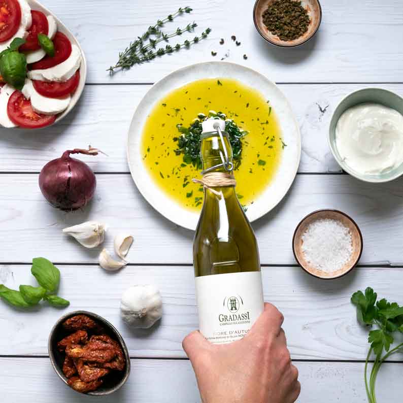 Olivenöl, Gewürze, Gemüse, Flasche mit Gradassi-Label, Teller, Hand.