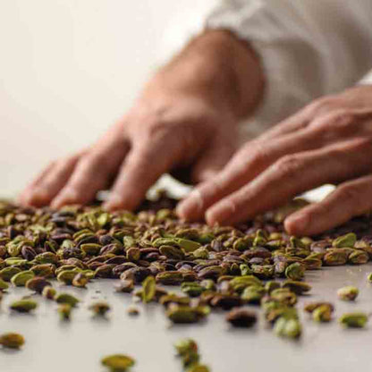 Hände sortieren Pistazien auf Tisch.