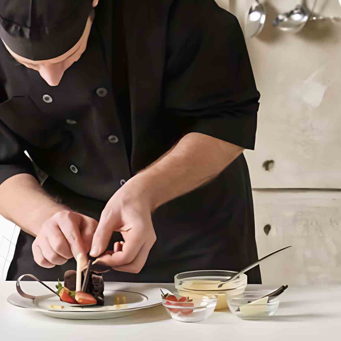 Koch dekoriert Dessert auf Teller.