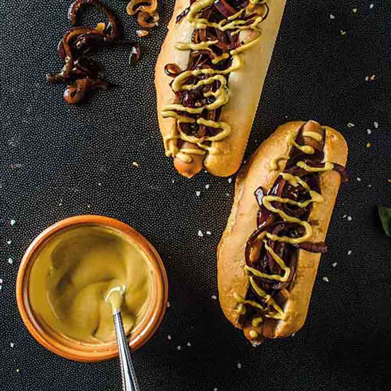 Feinkost: Hotdogs mit Senf und Zwiebeln, Schale mit Senf.