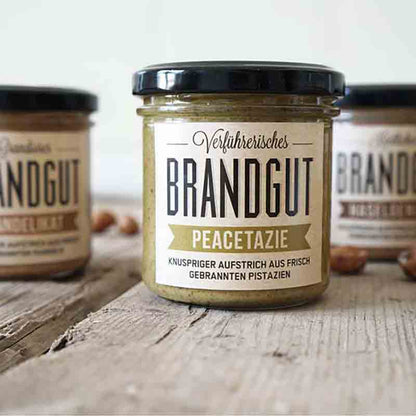 Drei Gläser Brandgut Peacetazie Aufstrich auf Holztisch.