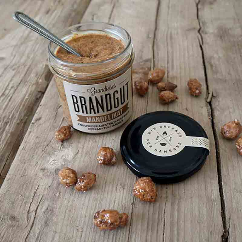 Glas Brandgut Mandelikat mit karamellisierten Mandeln auf Holztisch.