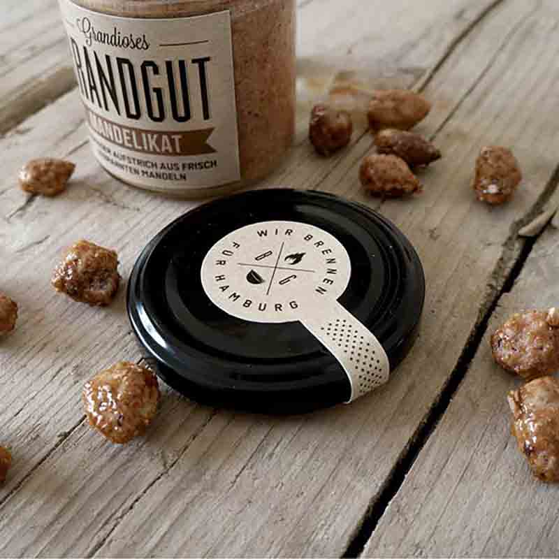 Glas mit Aufstrich, Nüsse, Holzuntergrund, Marke: Brandgut sichtbar.