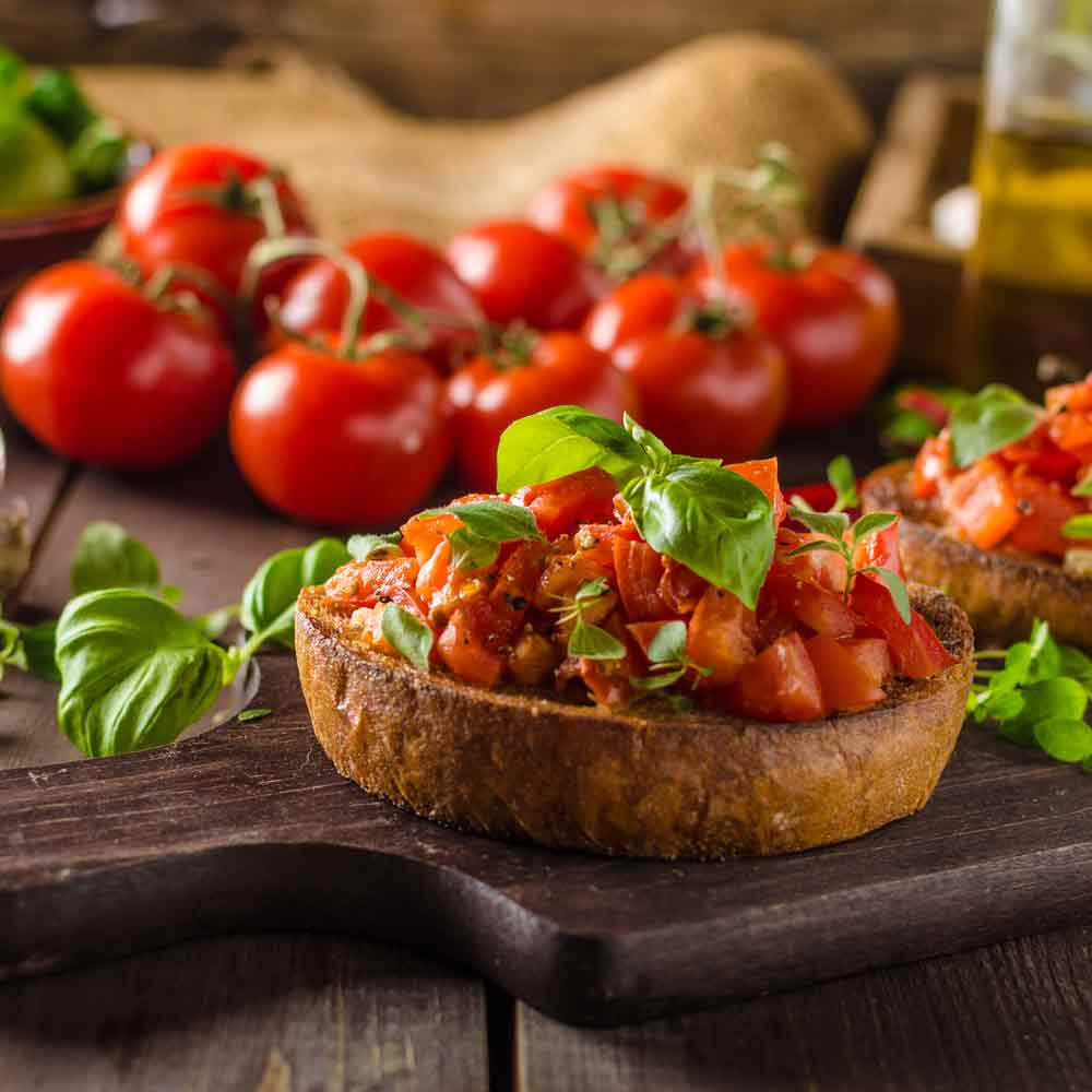 Bruschetta mit Tomaten und Basilikum auf Holzbrett.