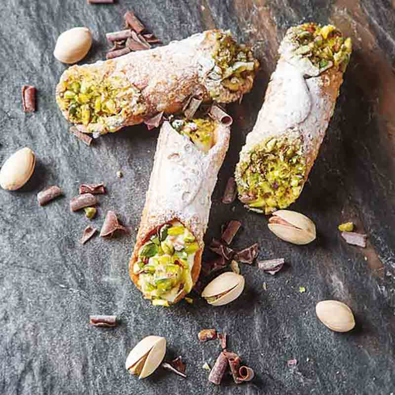 Cannoli mit Pistazien und Schokoladenstückchen auf Steinplatte.