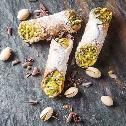 Cannoli mit Pistazien und Schokoladenstückchen auf Steinplatte.