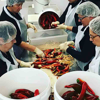 Personen verarbeiten rote Chilis in einer Produktionsumgebung.