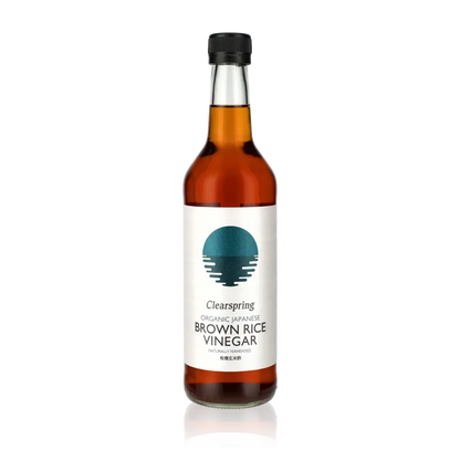 Clearspring brauner Reisessig Flasche vor schwarzem Hintergrund.