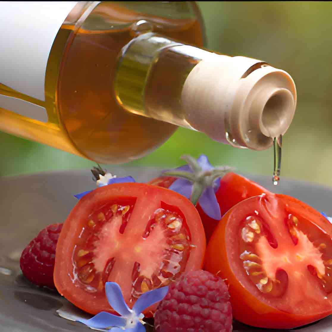 Flasche Essig über Tomaten, Himbeeren, blauen Blüten.