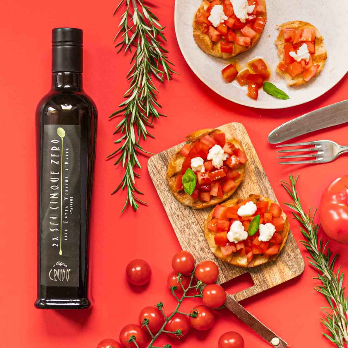 Flasche Olivenöl Crudo, Bruschetta, Tomaten, Rosmarin, Gabel, Messer.