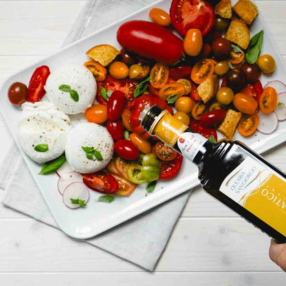 Teller mit Tomaten, Mozzarella, Brot, Olivenöl-Flasche.