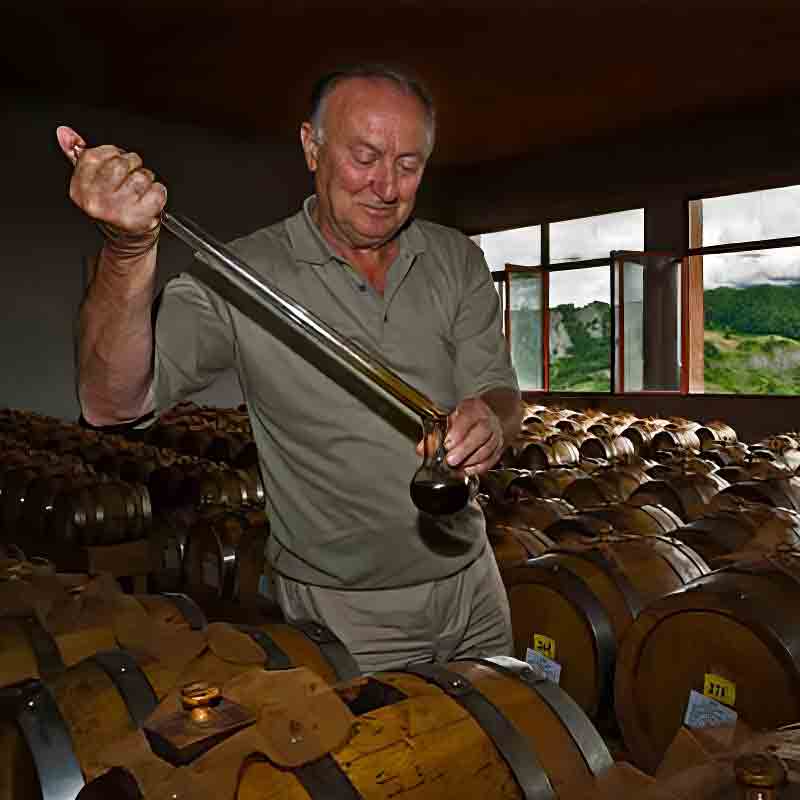 Mann prüft Essig in Holzfässern bei Acetaia Bertoni.