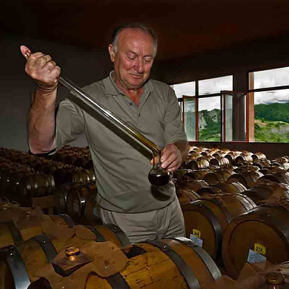Mann prüft Essig in Holzfässern bei Acetaia Bertoni.