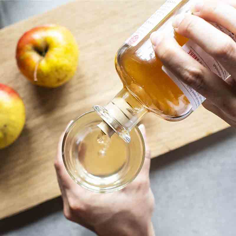 Dr. Höhl's Apfelessig wird in ein Glas gegossen.