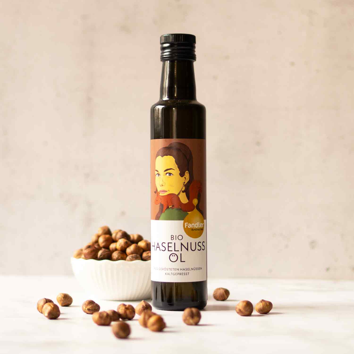 Fandler Haselnussöl-Flasche mit Schale voller Haselnüsse.