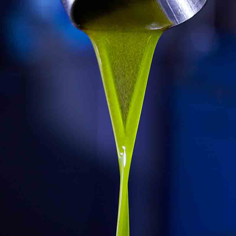 Olivenöl fließt aus Metallbehälter in dunkler Umgebung.