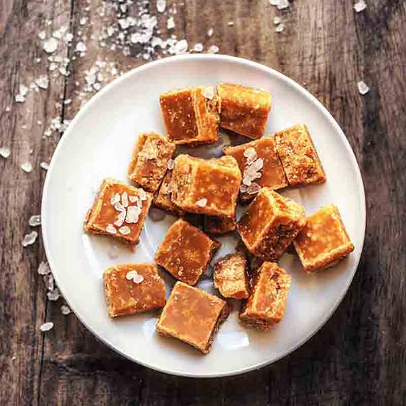 Fudge-Stücke auf Teller mit Salz bestreut auf Holztisch.