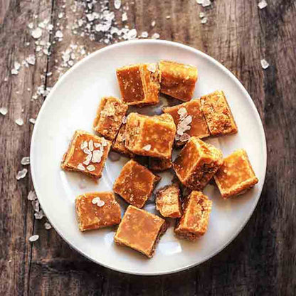 Fudge-Stücke auf Teller mit Salz bestreut auf Holztisch.
