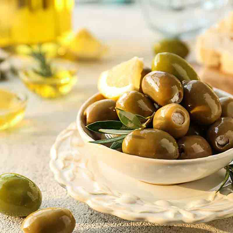 Gefüllte Oliven in Schale mit Olivenöl und Zitrone.