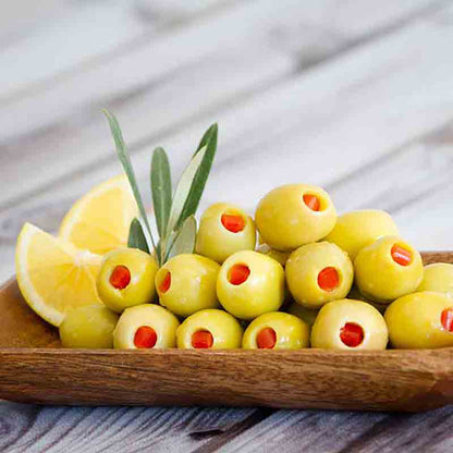 Gefüllte grüne Oliven auf Holzplatte mit Zitronenscheiben.