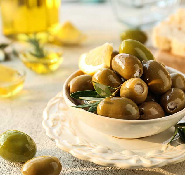 Gefüllte grüne Oliven in Schale mit Zitronenscheibe.