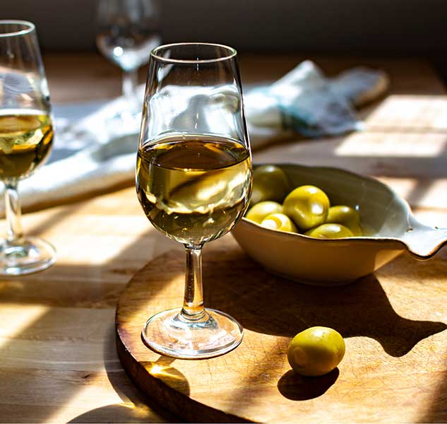 Weingläser und Schale mit gefüllten Oliven auf Tisch.