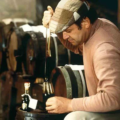 Mann füllt Balsamico-Essig aus kleinem Fass in Flasche.