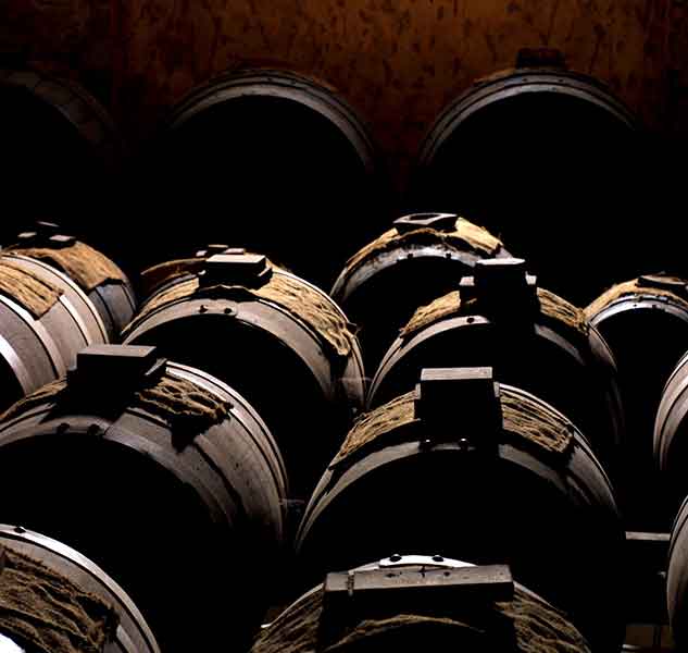 Holzfässer in dunklem Keller, Giusti Essigproduktion.
