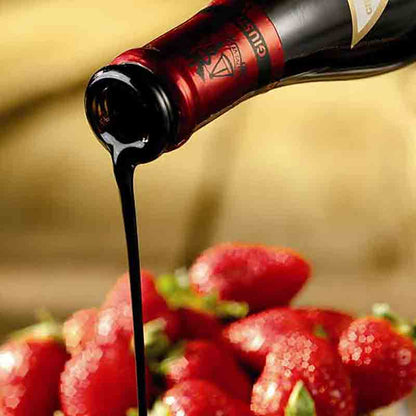 Giusti Balsamico wird über frische Erdbeeren gegossen.