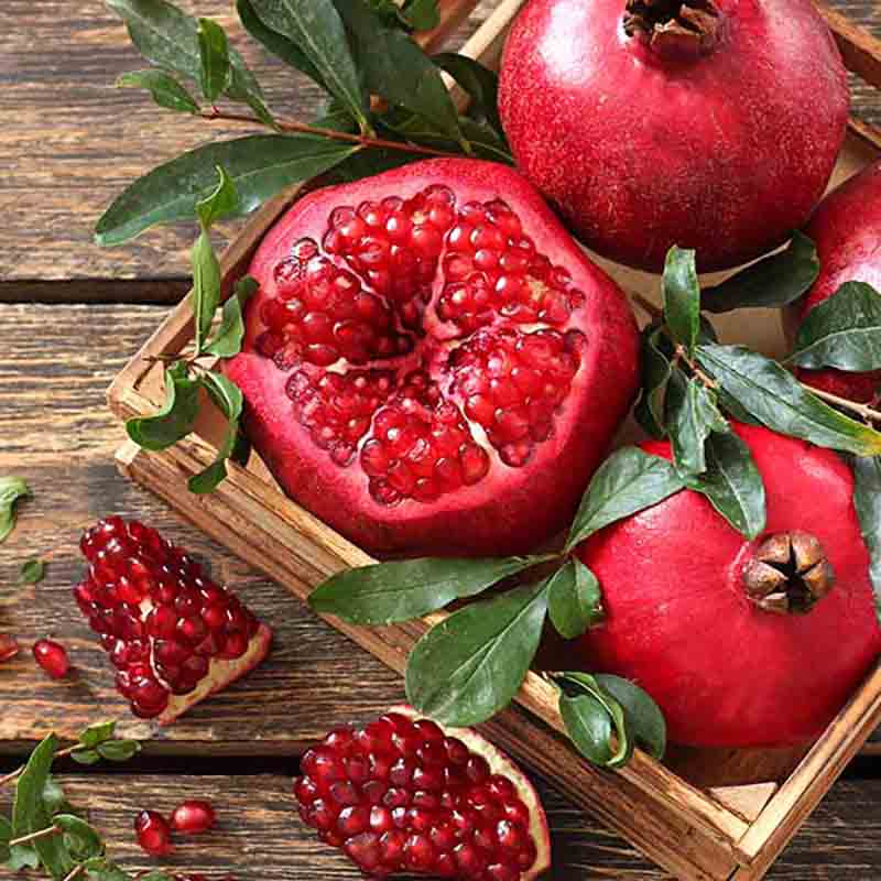 Granatäpfel in Holzkiste, aufgeschnitten.