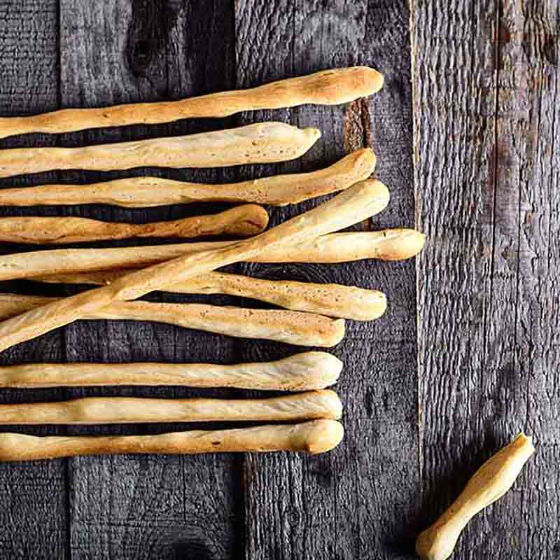 Grissini auf Holztisch, keine Delikatessen oder Marken sichtbar.