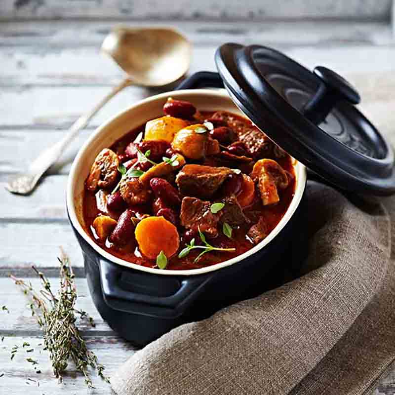 Gulasch in schwarzem Topf serviert.