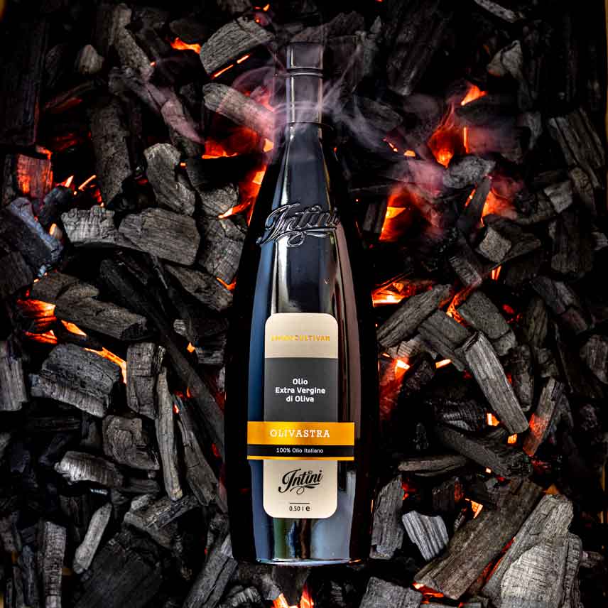 Intini Olivenölflasche auf glühenden Holzkohlen platziert.