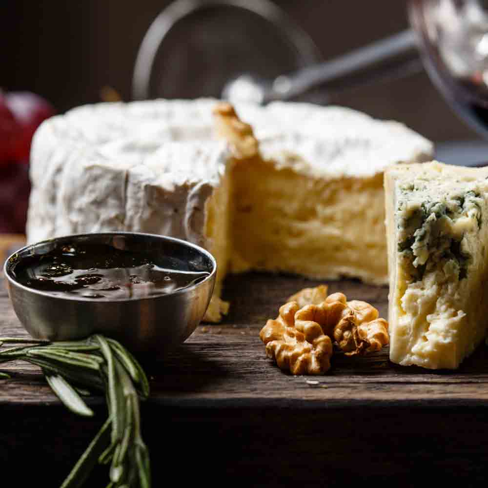 Käseplatte mit Senapata, Walnüssen und Rosmarin auf Holz.