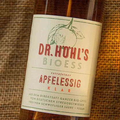 Dr. Höhl's Bioess Apfelessig Flasche auf Holzhintergrund.