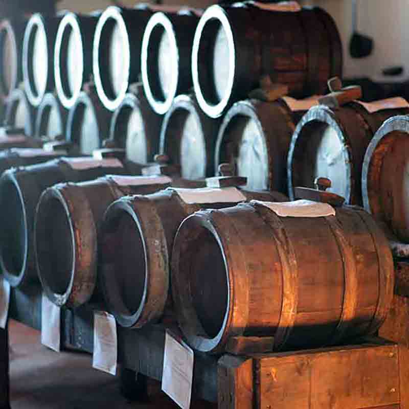 Holzfässer mit Essig in einem Lagerraum.