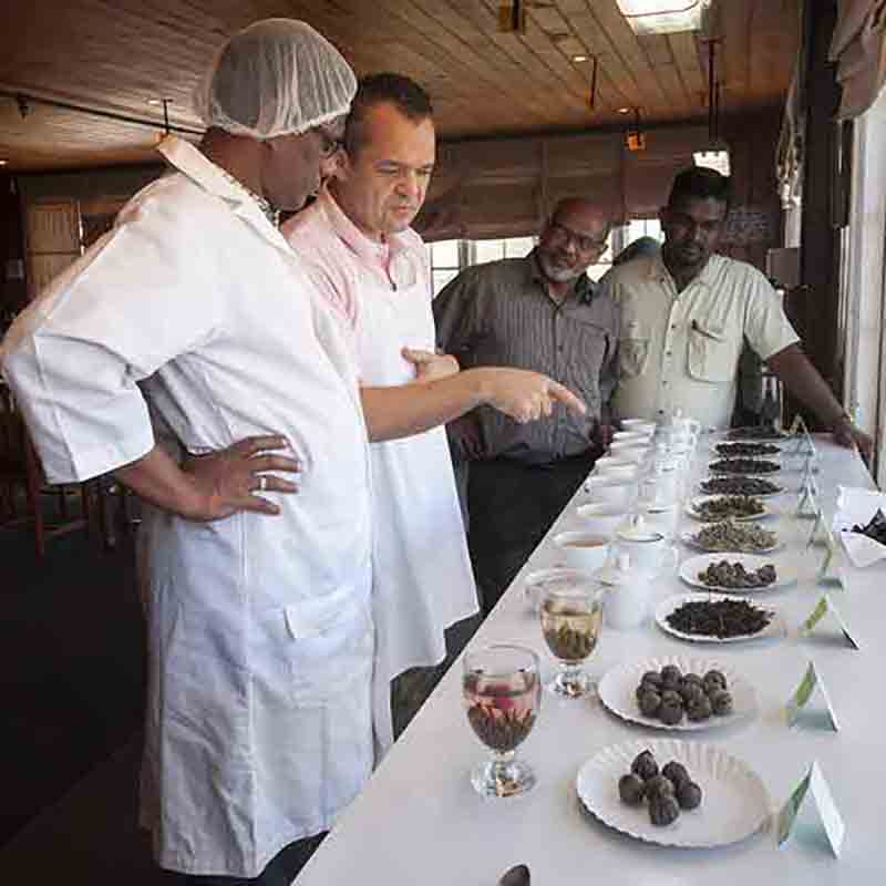 Männer begutachten Feinkost auf Tisch.