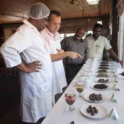 Männer begutachten Feinkost auf Tisch.